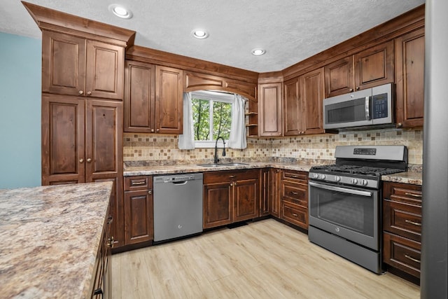 1127 8th St, Minot, ND 58703 - kitchen with appliances with stainless steel finishes, a sink, light wood finished floors, recessed lighting, and decorative backsplash