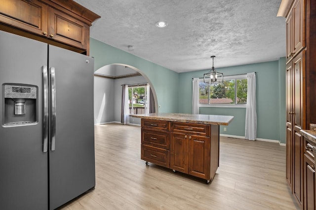 1127 8th St, Minot, ND 58703 - kitchen with stainless steel fridge with ice dispenser, arched walkways, a textured ceiling, baseboards, and light wood-type flooring
