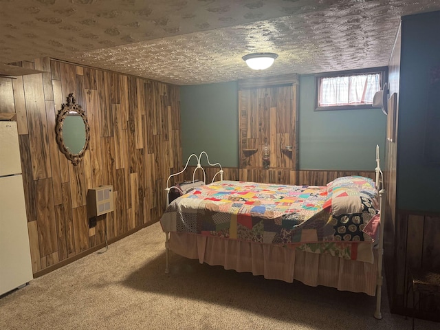 1130 8th St, Minot, ND 58703 - bedroom with wooden walls, freestanding refrigerator, carpet, heating unit, and a textured ceiling