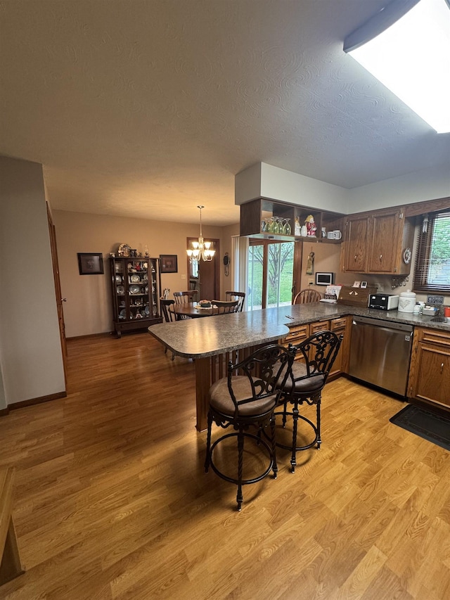 1130 8th St, Minot, ND 58703 - kitchen with stainless steel dishwasher, dark countertops, a chandelier, a peninsula, and light wood-type flooring