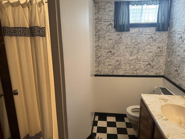 1130 8th St, Minot, ND 58703 - bathroom featuring toilet, wallpapered walls, tile patterned floors, vanity, and wainscoting