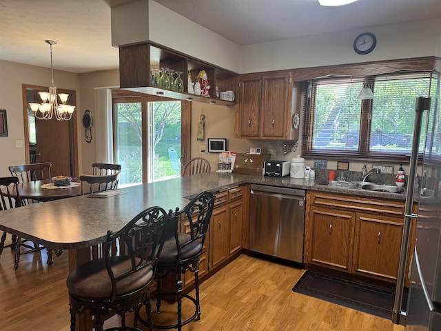 1130 8th St, Minot, ND 58703 - kitchen featuring dishwasher, a sink, light wood-style floors, a peninsula, and a chandelier