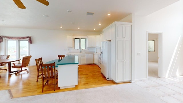 2700 18th Ave, Minot, ND 58701 - kitchen featuring white appliances, white cabinets, a sink, a kitchen breakfast bar, and a center island