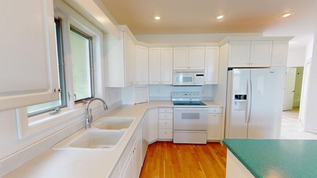 2700 18th Ave, Minot, ND 58701 - kitchen with white appliances, a sink, light wood-style flooring, white cabinets, and light countertops