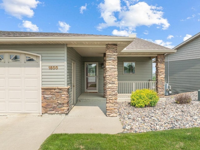 1600 16th St, Minot, ND 58701 - entrance to property with stone siding, covered porch, roof with shingles, and an attached garage