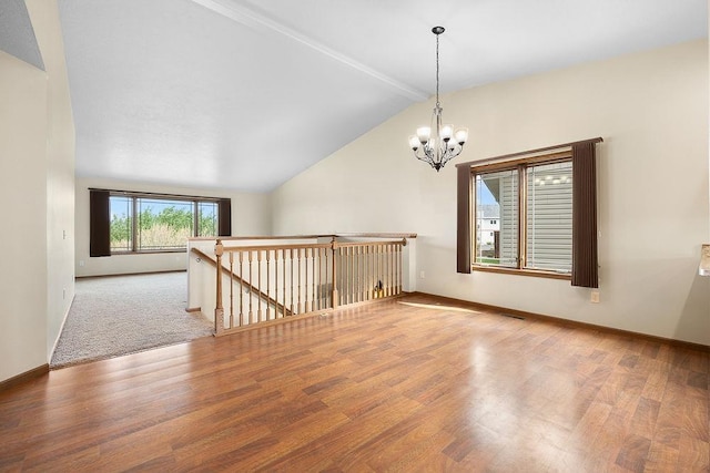 1600 16th St, Minot, ND 58701 - spare room with vaulted ceiling, wood finished floors, a chandelier, and baseboards