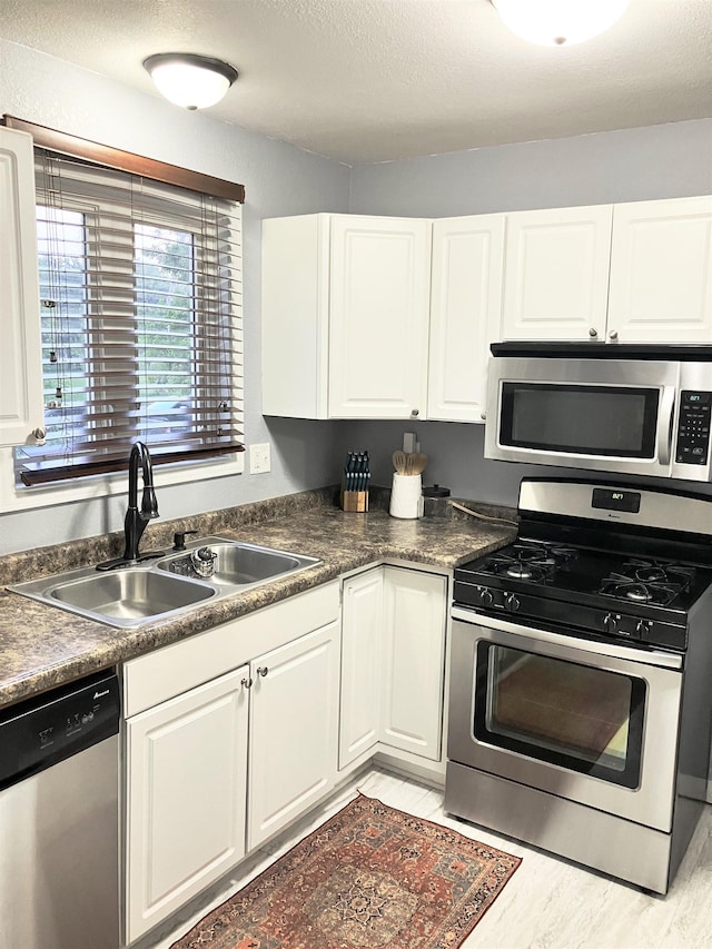 430 NW 2nd Ave, Minot, ND 58703 - kitchen featuring appliances with stainless steel finishes, a sink, white cabinetry, and dark countertops