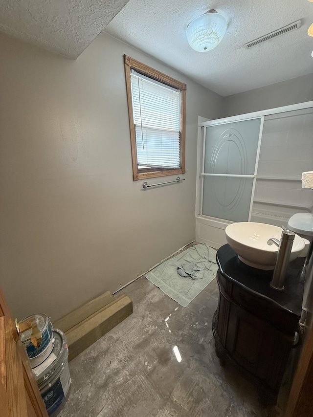 619 25th Ave, Minot, ND 58703 - full bath with a textured ceiling, vanity, and combined bath / shower with glass door