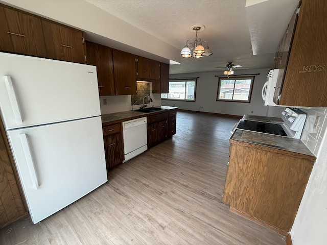619 25th Ave, Minot, ND 58703 - kitchen featuring white appliances, a sink, a chandelier, light wood-type flooring, and dark brown cabinetry