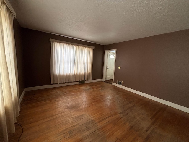 1107 SE 2nd St, Minot, ND 58701 - spare room with wood finished floors, a textured ceiling, and baseboards