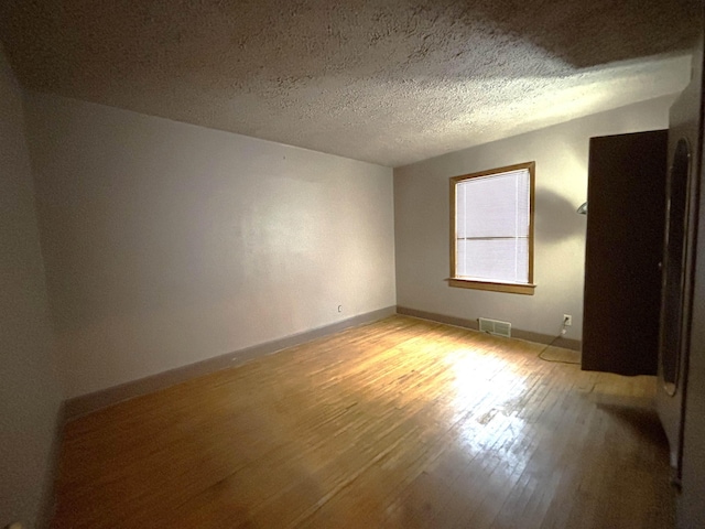 1107 SE 2nd St, Minot, ND 58701 - spare room with light wood finished floors, baseboards, and a textured ceiling