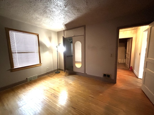 1107 SE 2nd St, Minot, ND 58701 - unfurnished bedroom featuring light wood finished floors, a textured ceiling, and baseboards