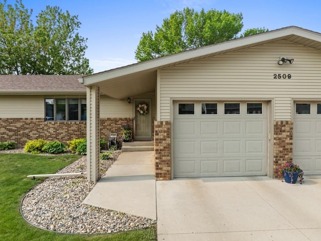 2509 11th Ave, Minot, ND 58703 - view of front of house featuring brick siding, concrete driveway, and an attached garage