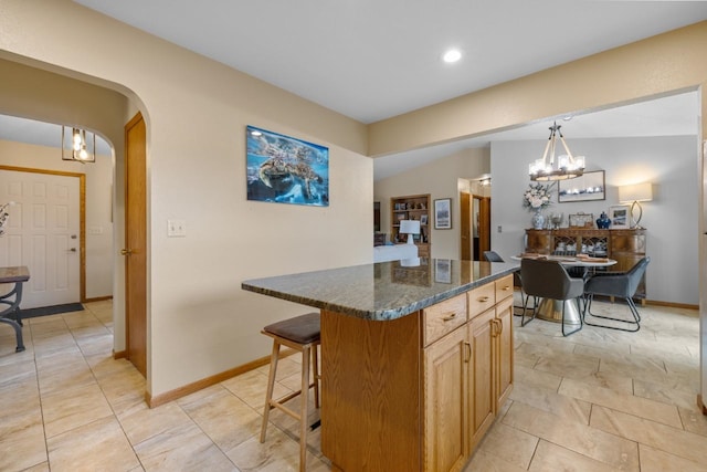 2509 11th Ave, Minot, ND 58703 - kitchen featuring a chandelier, a breakfast bar area, arched walkways, a center island, and baseboards