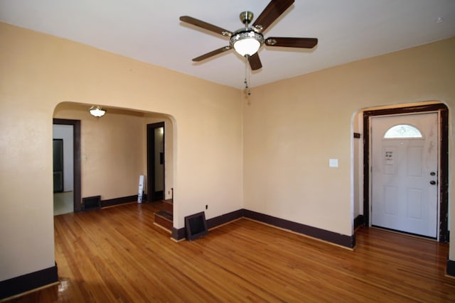 820 SW 5th St, Minot, ND 58701 - empty room featuring arched walkways, ceiling fan, wood finished floors, and baseboards