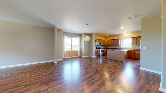 2947 8th St, Minot, ND 58703 - kitchen with appliances with stainless steel finishes, open floor plan, dark wood-style flooring, a center island, and baseboards