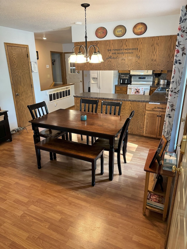919 9th St, Minot, ND 58703 - dining space with light wood-style flooring, a chandelier, and a textured ceiling