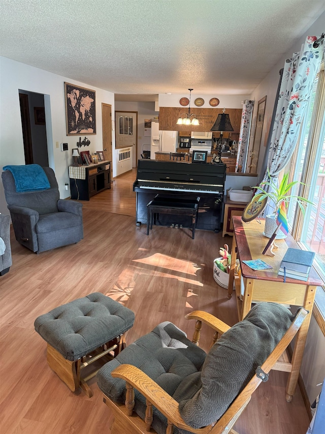 919 9th St, Minot, ND 58703 - living area featuring radiator, a textured ceiling, wood finished floors, and a chandelier