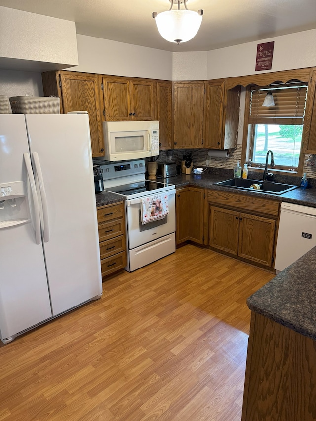 919 9th St, Minot, ND 58703 - kitchen with white appliances, a sink, dark countertops, light wood-type flooring, and brown cabinets