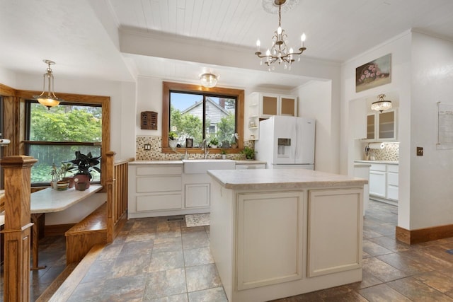 901 3rd St, Minot, ND 58701 - kitchen featuring a sink, white fridge with ice dispenser, tasteful backsplash, stone tile floors, and ornamental molding