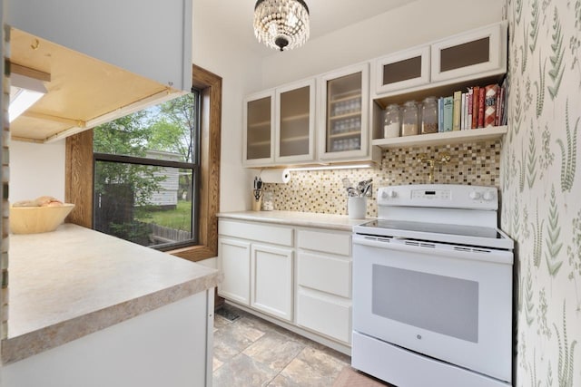 901 3rd St, Minot, ND 58701 - kitchen featuring white electric stove, backsplash, light countertops, stone finish flooring, and white cabinetry