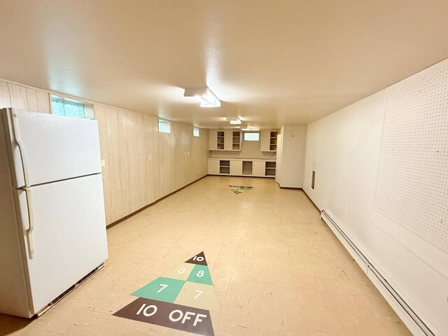 30 1st St, Sawyer, ND 58781 - basement featuring freestanding refrigerator, light flooring, and a baseboard radiator