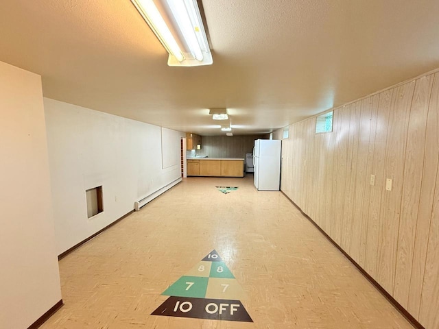 30 1st St, Sawyer, ND 58781 - basement with freestanding refrigerator, baseboard heating, baseboards, and wood walls