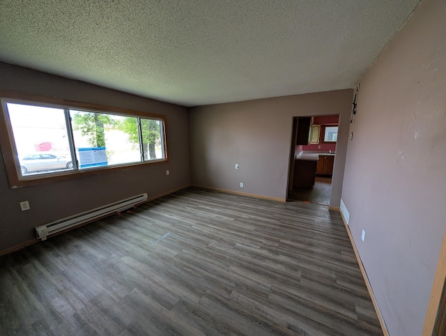 2704 SE 9th Ave, Minot, ND 58701 - empty room featuring a baseboard heating unit, a textured ceiling, wood finished floors, and baseboards