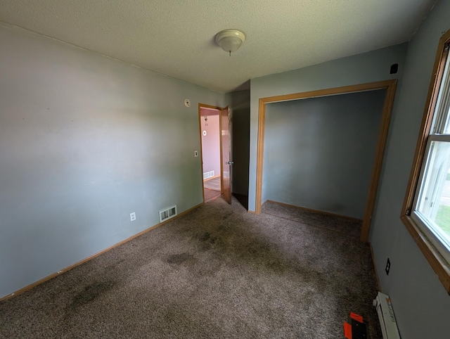 2704 SE 9th Ave, Minot, ND 58701 - unfurnished bedroom with carpet, a closet, a baseboard radiator, and a textured ceiling