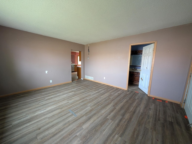 2704 SE 9th Ave, Minot, ND 58701 - unfurnished bedroom with wood finished floors, baseboards, and a textured ceiling