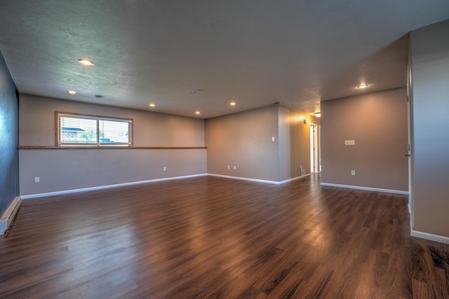 3421 8th St, Minot, ND 58703 - empty room featuring dark wood-style floors, baseboards, recessed lighting, and a baseboard heating unit