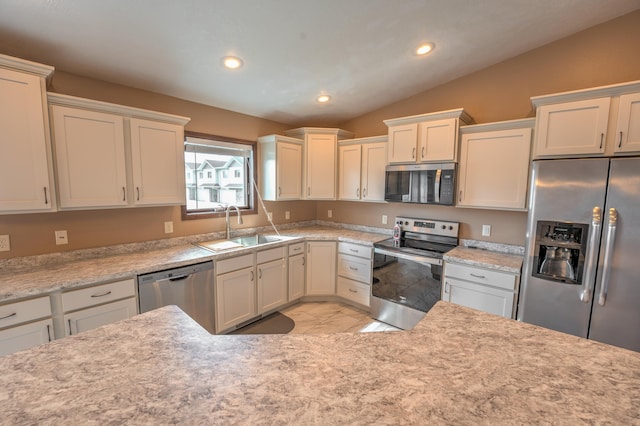 3421 8th St, Minot, ND 58703 - kitchen featuring appliances with stainless steel finishes, a sink, lofted ceiling, white cabinets, and recessed lighting