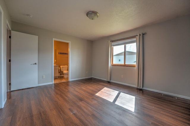 3421 8th St, Minot, ND 58703 - unfurnished bedroom with dark wood-type flooring, baseboards, and ensuite bath