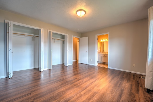 3421 8th St, Minot, ND 58703 - unfurnished bedroom featuring multiple closets, dark wood-style floors, and baseboards