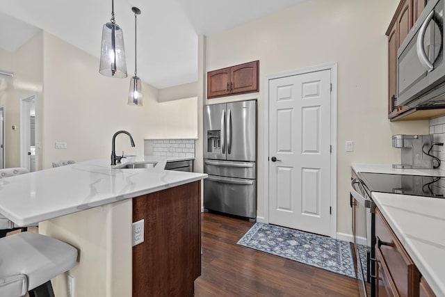 1321 Golden Valley Ln, Minot, ND 58703 - kitchen featuring appliances with stainless steel finishes, a sink, a breakfast bar area, dark wood-style flooring, and hanging light fixtures