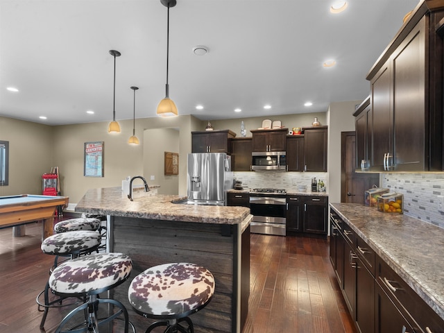 6125 11th Ave, Minot, ND 58701 - kitchen with stainless steel appliances, dark wood-style floors, tasteful backsplash, dark brown cabinets, and recessed lighting
