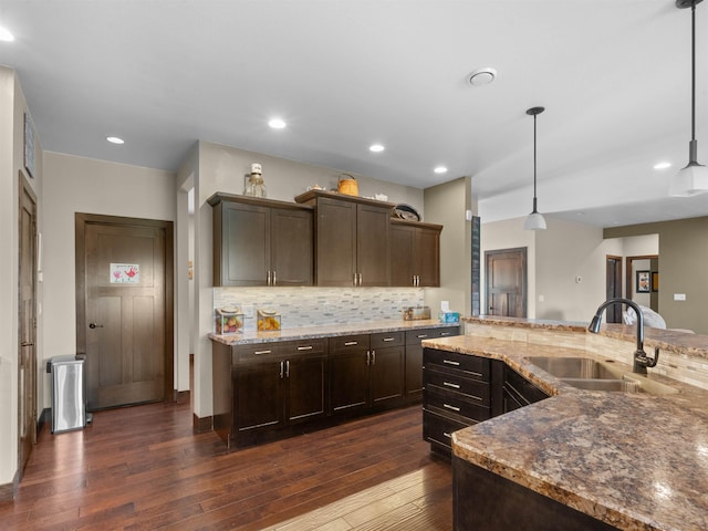 6125 11th Ave, Minot, ND 58701 - kitchen with a sink, dark wood finished floors, dark brown cabinetry, tasteful backsplash, and light stone counters