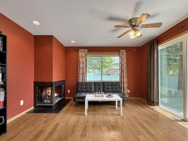 424 26th St, Minot, ND 58703 - living room featuring a multi sided fireplace, a ceiling fan, wood finished floors, baseboards, and recessed lighting