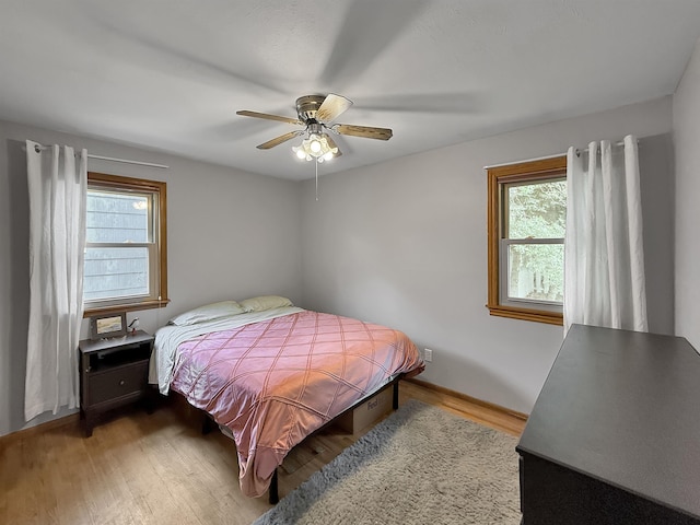 424 26th St, Minot, ND 58703 - bedroom featuring multiple windows, wood finished floors, ceiling fan, and baseboards
