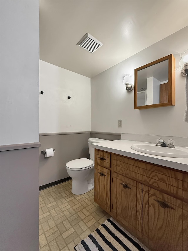 424 26th St, Minot, ND 58703 - bathroom featuring vanity, brick patterned flooring, and toilet