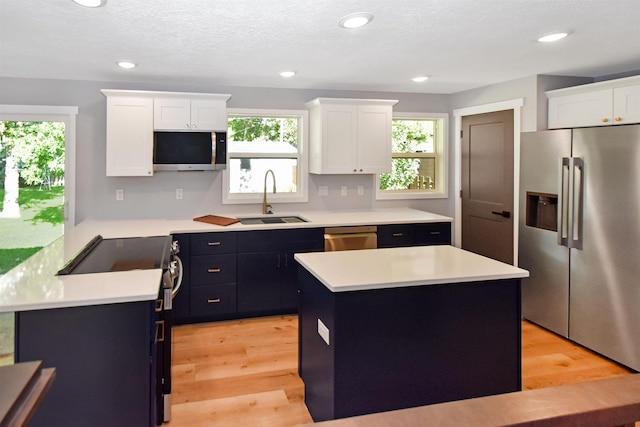 1821 11th St, Minot, ND 58701 - kitchen featuring stainless steel appliances, a sink, light countertops, white cabinets, and plenty of natural light
