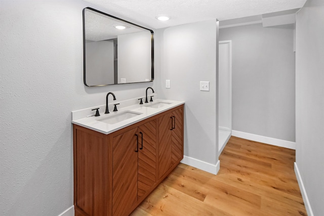 1821 11th St, Minot, ND 58701 - bathroom featuring double vanity, wood finished floors, baseboards, and a textured ceiling