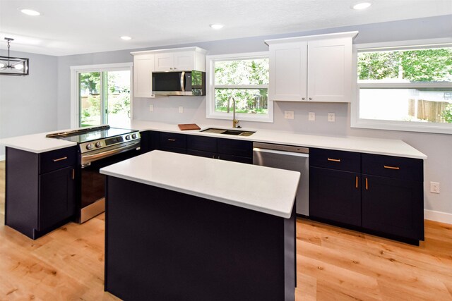1821 11th St, Minot, ND 58701 - kitchen with a sink, stainless steel appliances, white cabinetry, a peninsula, and light countertops