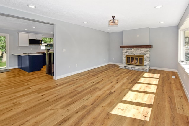 1821 11th St, Minot, ND 58701 - unfurnished living room featuring plenty of natural light, light wood finished floors, a stone fireplace, and recessed lighting