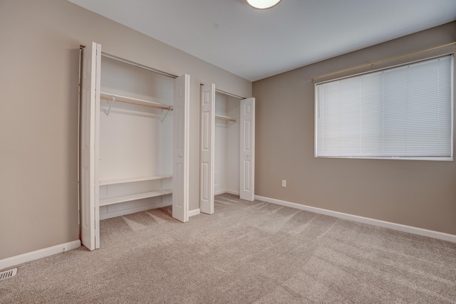 3328 NW 20th Ave, Minot, ND 58703 - unfurnished bedroom featuring two closets, carpet, and baseboards