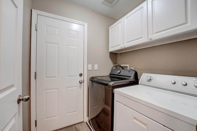 3328 NW 20th Ave, Minot, ND 58703 - washroom with cabinet space, washing machine and clothes dryer, and light wood finished floors