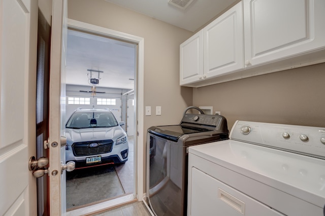 3328 NW 20th Ave, Minot, ND 58703 - washroom featuring cabinet space, washer and dryer, and light wood-style floors