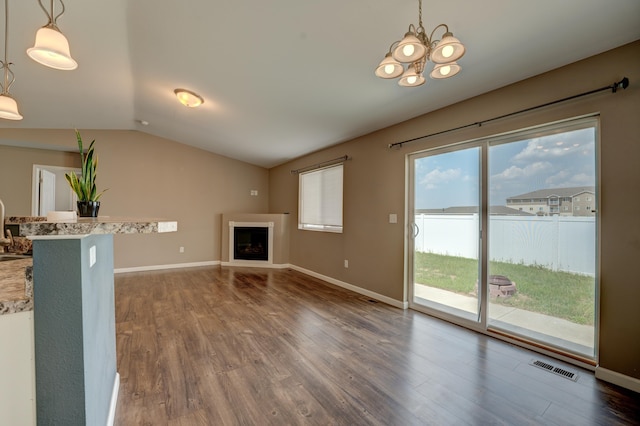 3328 NW 20th Ave, Minot, ND 58703 - unfurnished living room featuring wood finished floors, vaulted ceiling, a chandelier, a fireplace, and baseboards