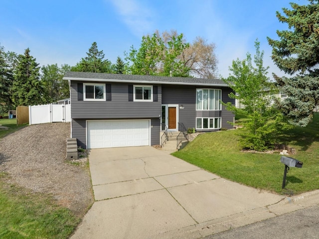 1925 10th St, Minot, ND 58703 - raised ranch with concrete driveway, a garage, a gate, and a front yard
