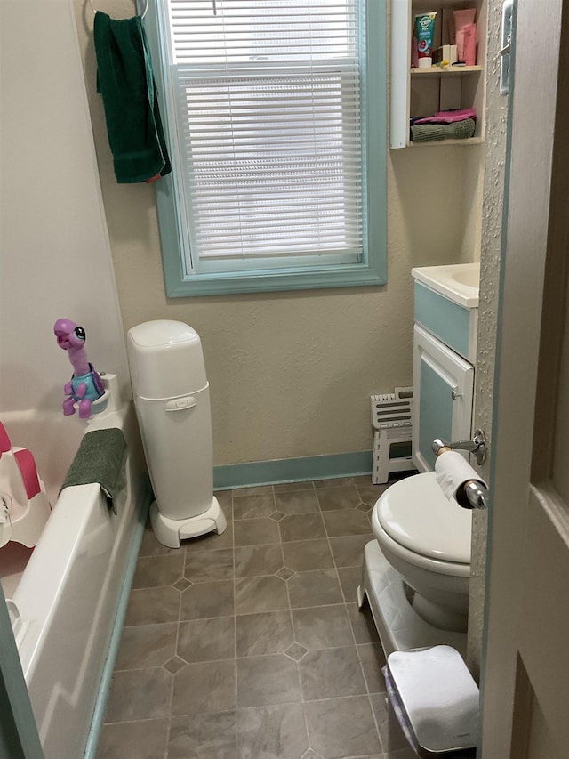 525 12th St, Minot, ND 58703 - bathroom with vanity, toilet, baseboards, and a tub